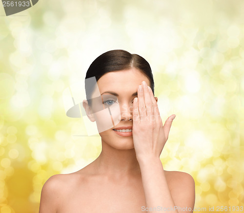 Image of smiling young woman covering face with hand