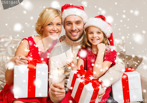 Image of smiling family holding gift boxes and sparkles