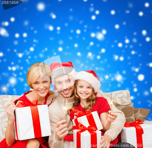 Image of smiling family holding gift boxes and sparkles