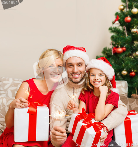 Image of smiling family holding gift boxes and sparkles