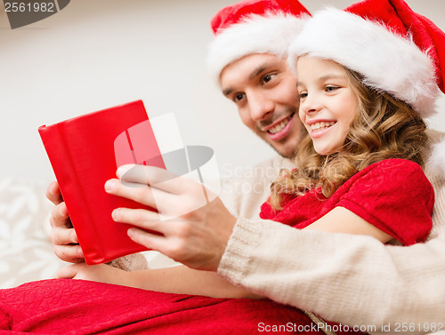 Image of smiling father and daughter reading book
