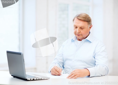 Image of old man filling a form at home