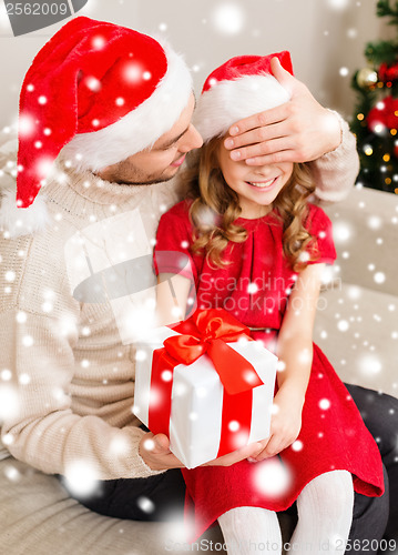 Image of smiling father surprises daughter with gift box