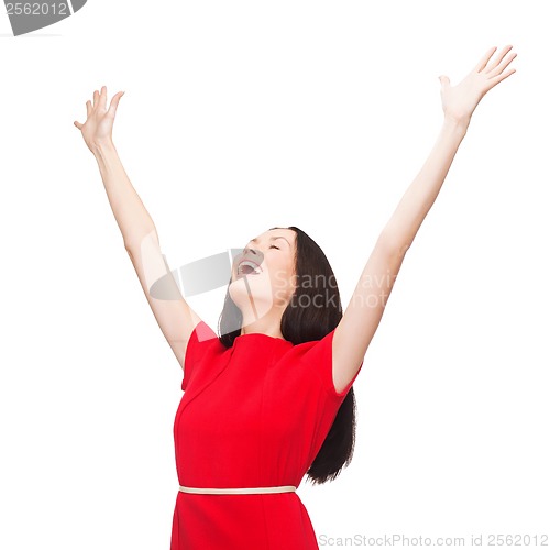 Image of smiling young woman in red dress waving hands