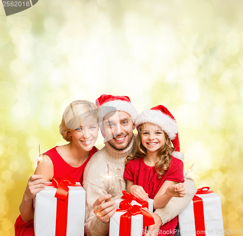 Image of smiling family holding gift boxes and sparkles