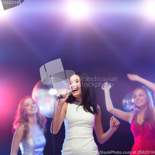 Image of three smiling women dancing and singing karaoke