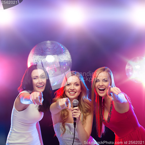 Image of three smiling women dancing and singing karaoke