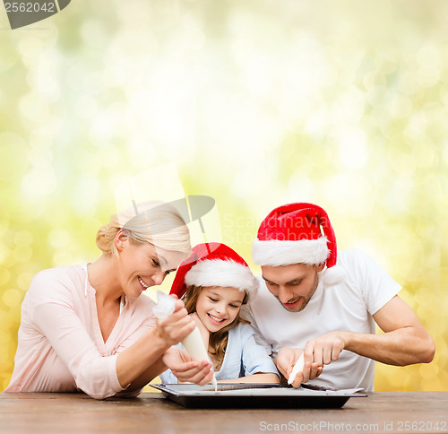 Image of happy family in santa helper hats making cookies