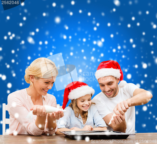 Image of happy family in santa helper hats making cookies