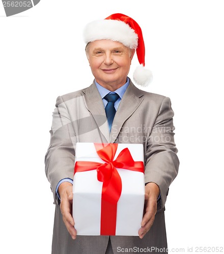 Image of smiling man in suit and santa helper hat with gift