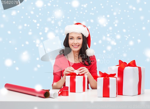 Image of woman in santa helper hat with many gift boxes