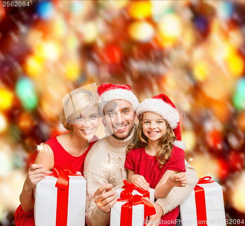 Image of smiling family holding gift boxes and sparkles