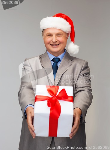 Image of smiling man in suit and santa helper hat with gift