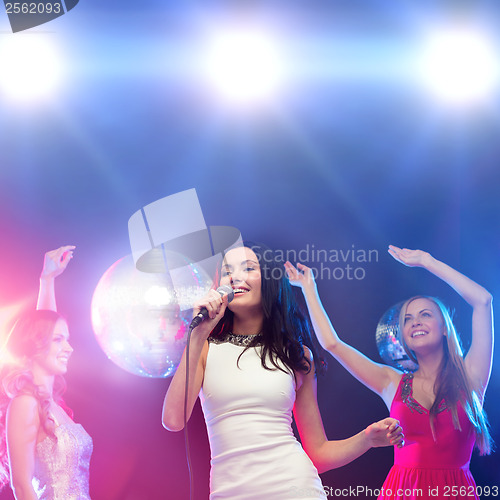 Image of three smiling women dancing and singing karaoke