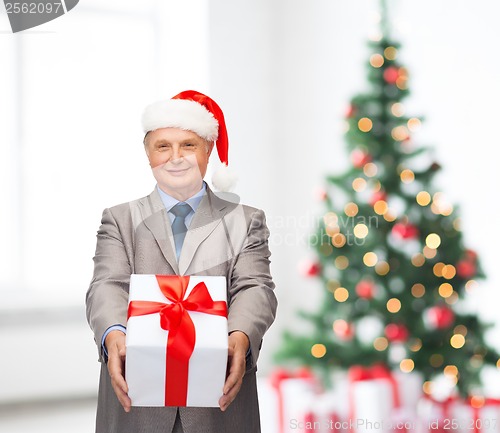 Image of smiling man in suit and santa helper hat with gift