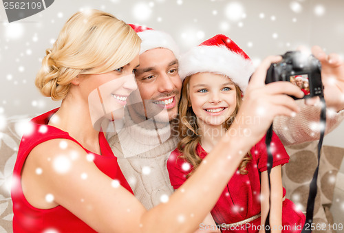 Image of smiling family in santa helper hats taking picture