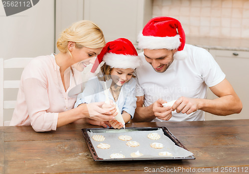 Image of happy family in santa helper hats making cookies