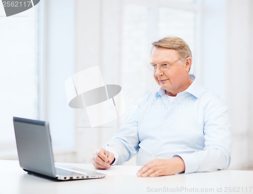 Image of old man in eyeglasses filling a form at home