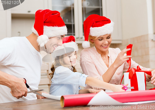 Image of smiling family in santa helper hats with gift box