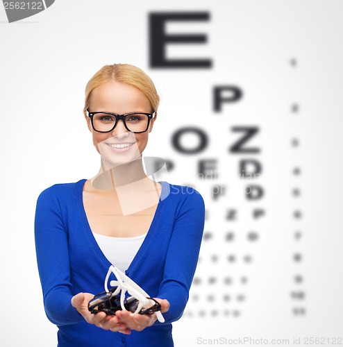 Image of smiling woman wearing and holding eyeglasses