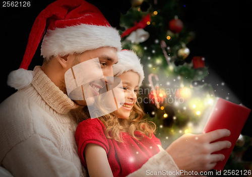 Image of smiling father and daughter reading book