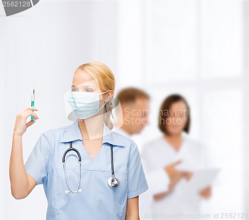 Image of female doctor or nurse in mask holding syringe