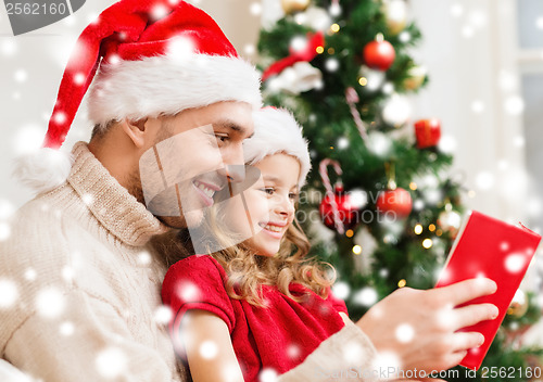 Image of smiling father and daughter reading book