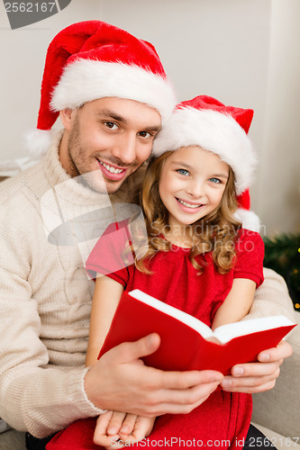 Image of smiling father and daughter reading book