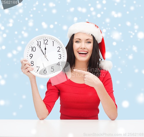 Image of woman in santa helper hat with clock showing 12