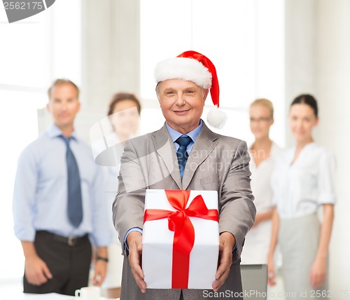 Image of smiling man in suit and santa helper hat with gift