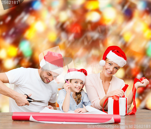 Image of smiling family in santa helper hats with gift box