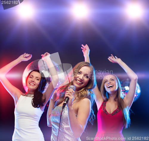 Image of three smiling women dancing and singing karaoke