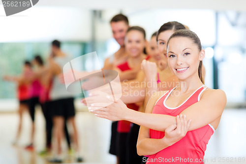 Image of group of smiling people stretching in the gym