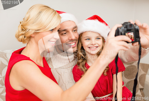 Image of smiling family in santa helper hats taking picture
