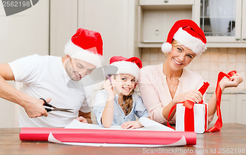 Image of smiling family in santa helper hats with gift box