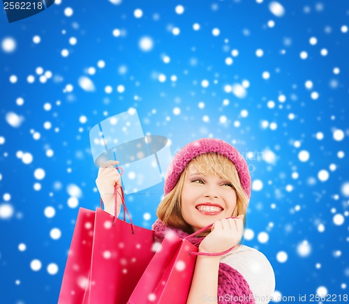 Image of woman in pink hat and scarf with shopping bags