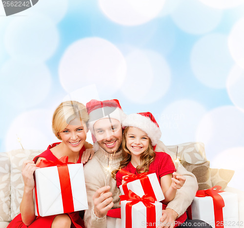 Image of smiling family holding gift boxes and sparkles