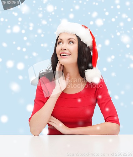 Image of surprised woman in santa helper hat looking up