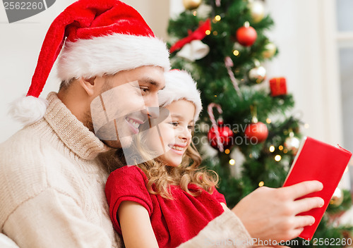 Image of smiling father and daughter reading book