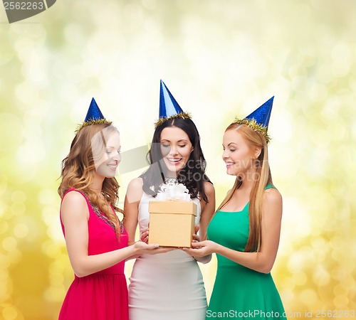 Image of three smiling women in blue hats with gift box