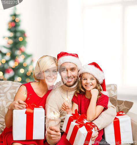 Image of smiling family holding gift boxes and sparkles