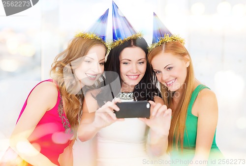 Image of three smiling women in hats having fun with camera