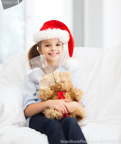 Image of smiling girl in santa helper hat with teddy bear
