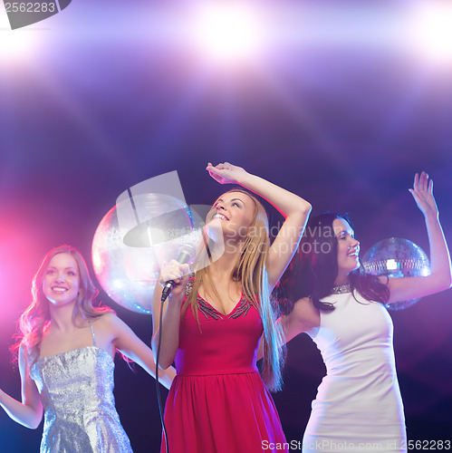 Image of three smiling women dancing and singing karaoke