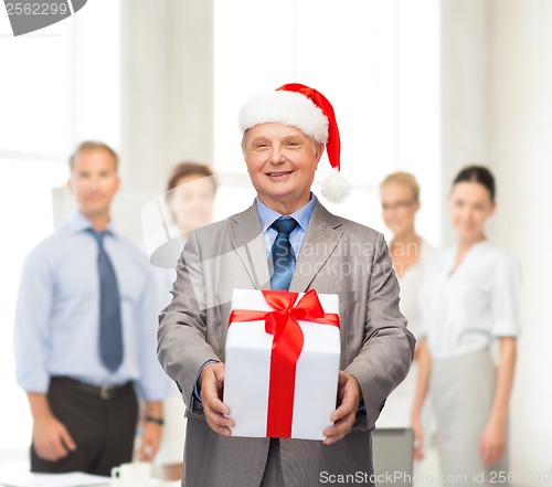 Image of smiling man in suit and santa helper hat with gift