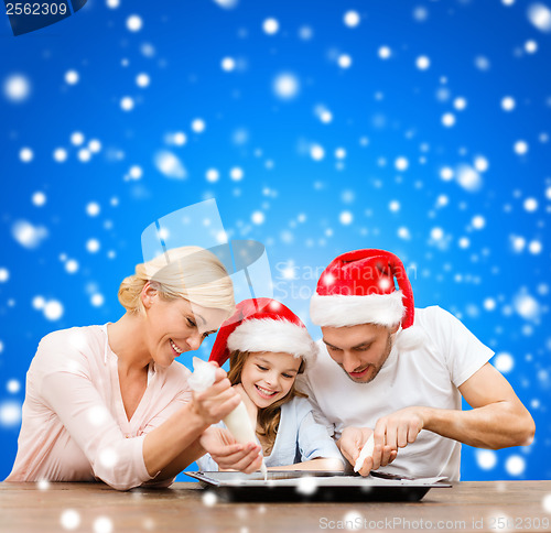 Image of happy family in santa helper hats making cookies