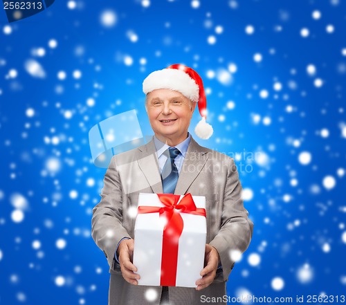 Image of smiling man in suit and santa helper hat with gift