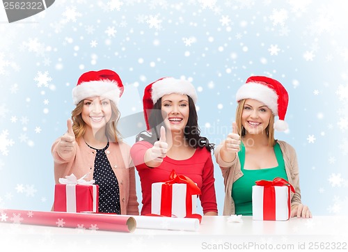 Image of smiling women in santa helper hats with gift boxes