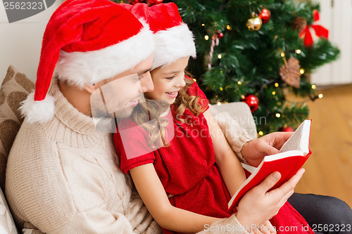 Image of smiling father and daughter reading book