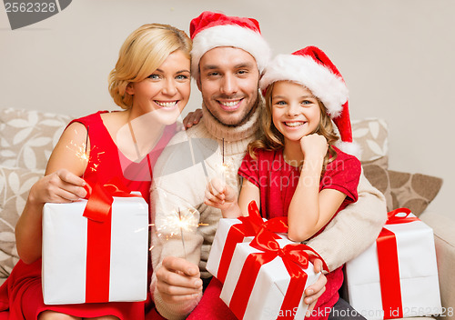 Image of smiling family holding gift boxes and sparkles